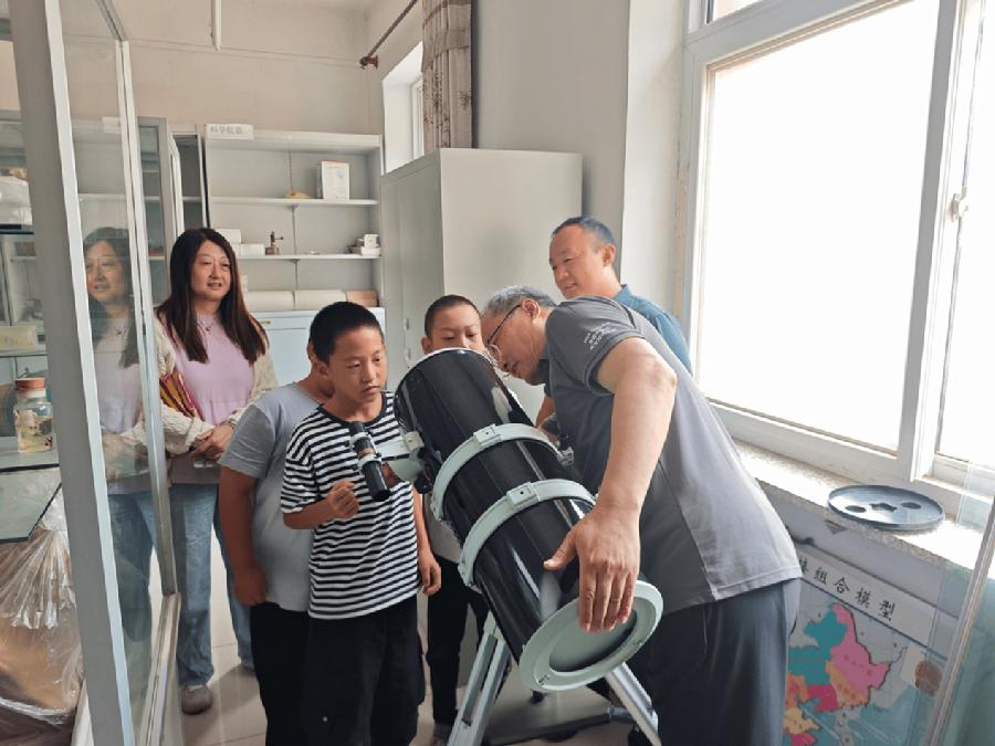 天文科普专家和驻松棚村干部在指导学生使用望远镜